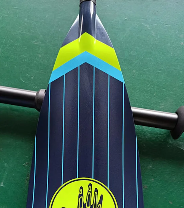 Paddle blade with blue lines and yellow and blue chevrons on a dark surface