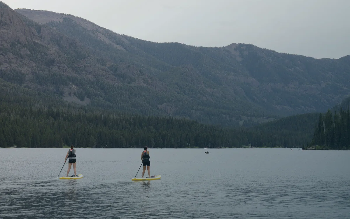 Two stand up paddlers on a mountain reservoir for a paddle length selection guide